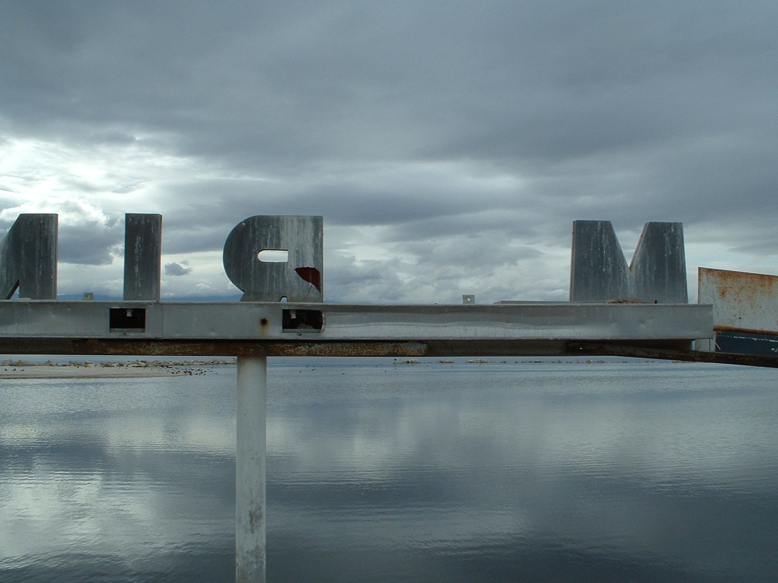 Weathered metal letters against water and storm clouds